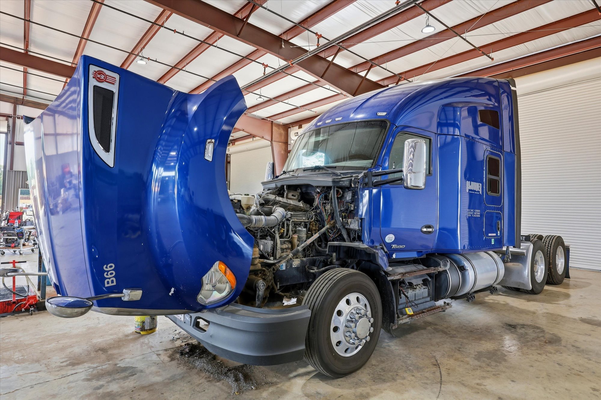 Blue Peterbilt with cowl tipped up inside a Wilkerson service bay